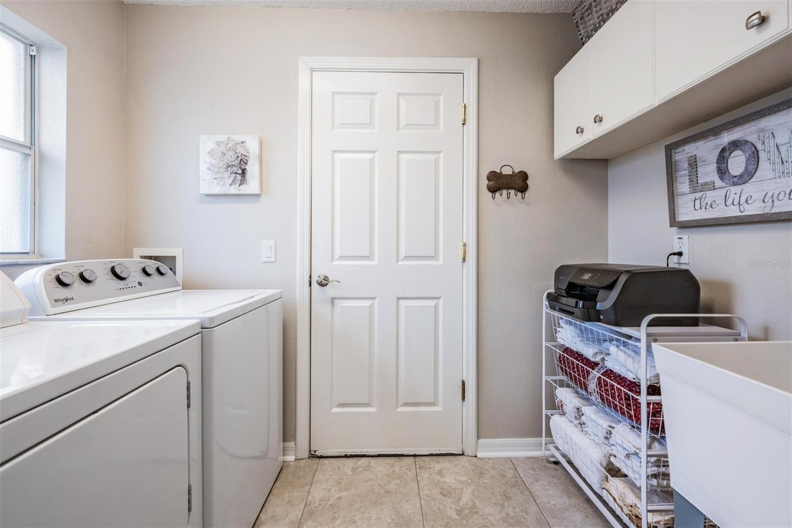 Walk-in laundry room with utility sink and built-in cabinets