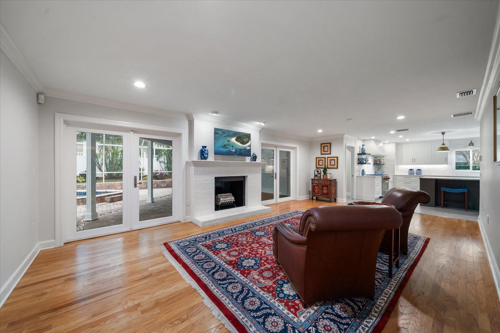 Family room flows into the pool area with covered lanai through lovely French doors.