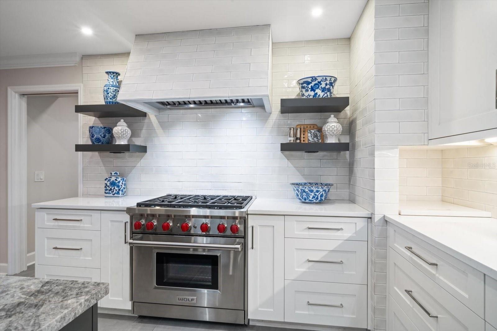 Six burner gas Wolfe Range with attractive hood complements the detailing of the backsplash.