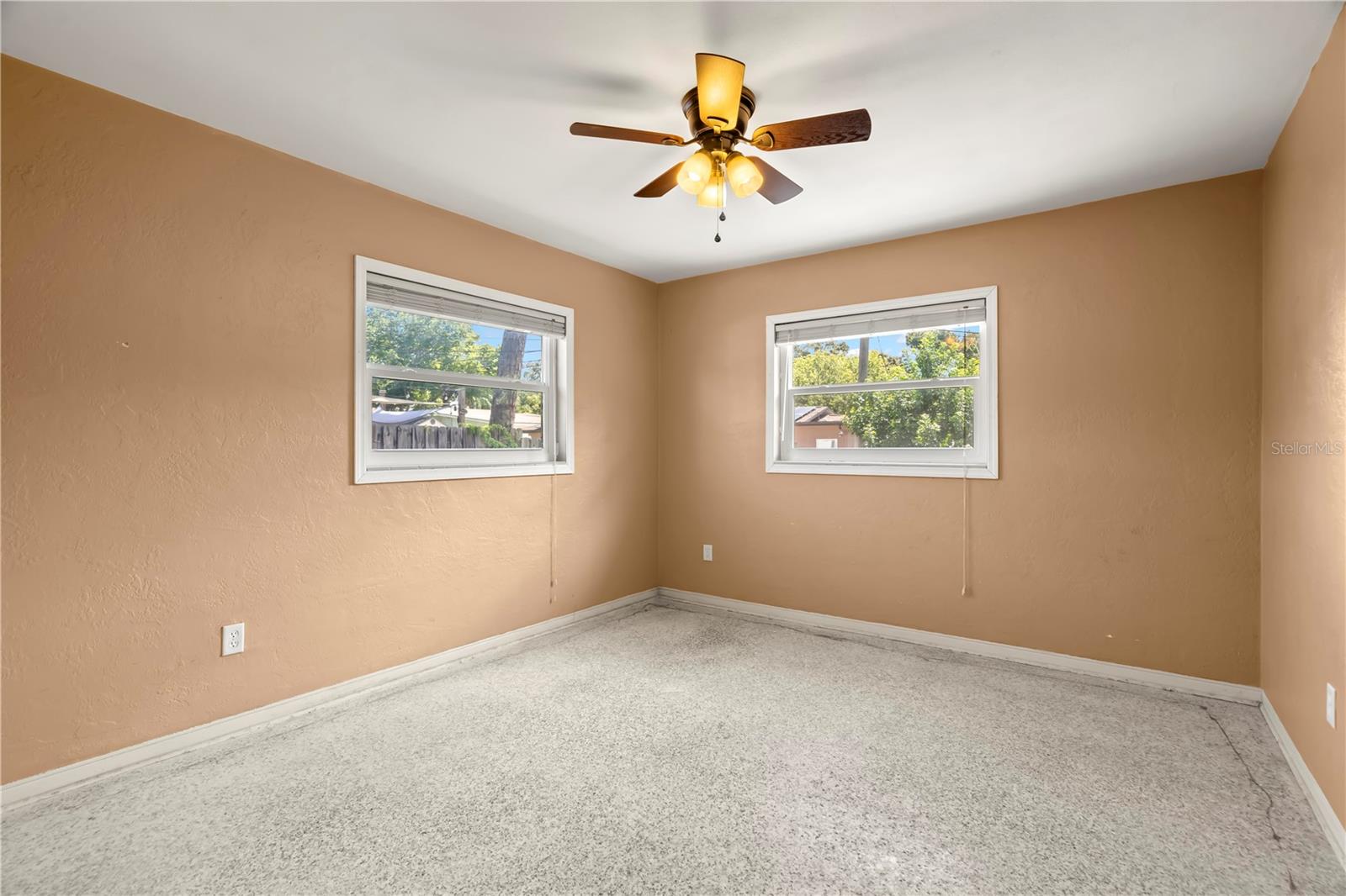 2nd bedroom with ceiling fan. Carpets have been ripped up so you can install your own flooring or leave the terrazzo underneath