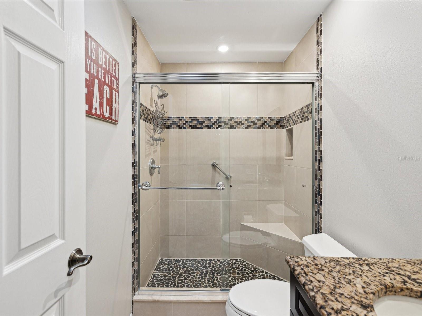 Guest Bath w/ Granite Sink and decorative tiled walk in shower.