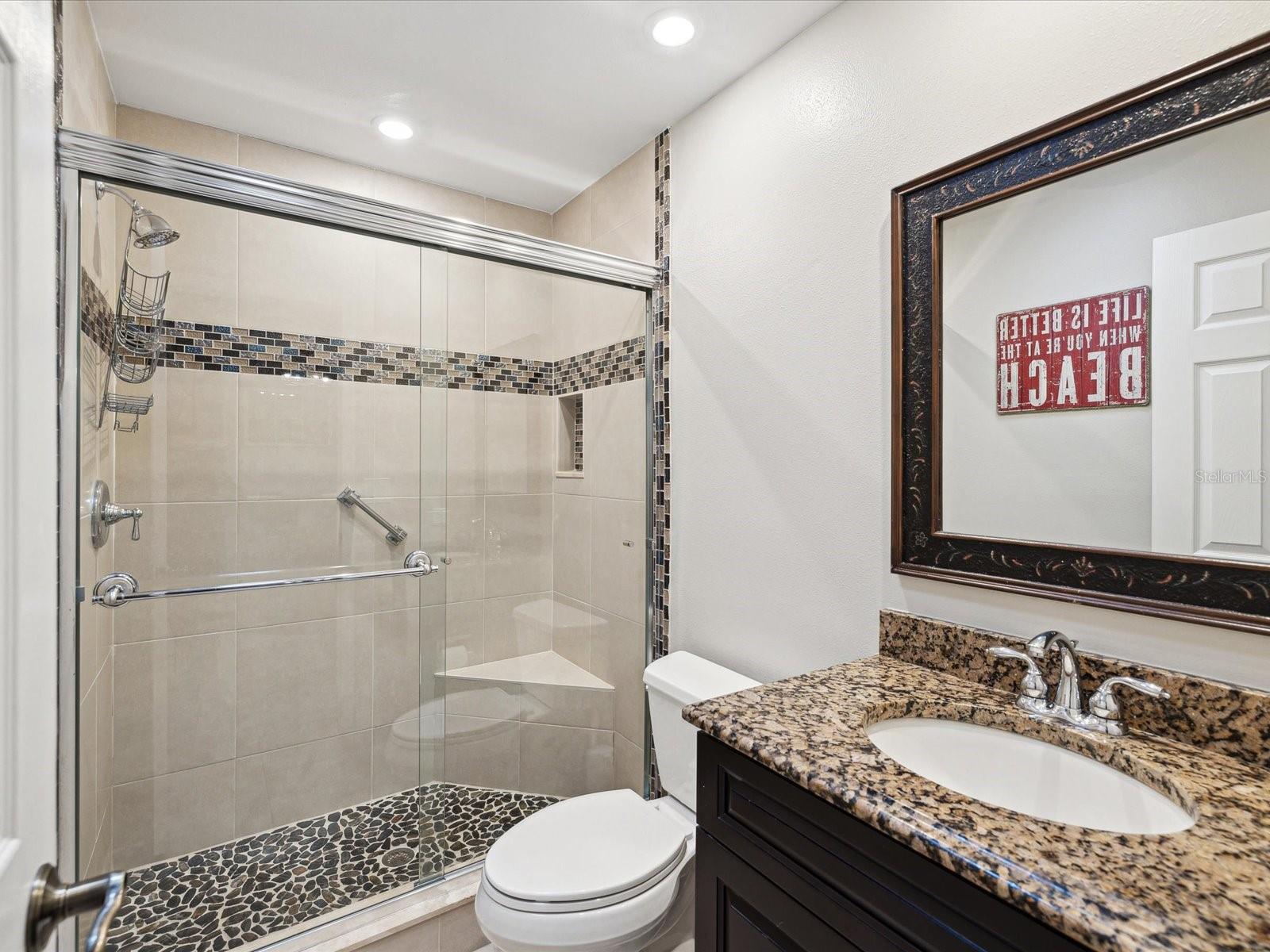 Guest Bath w/ Granite Sink and decorative tiled Shower.