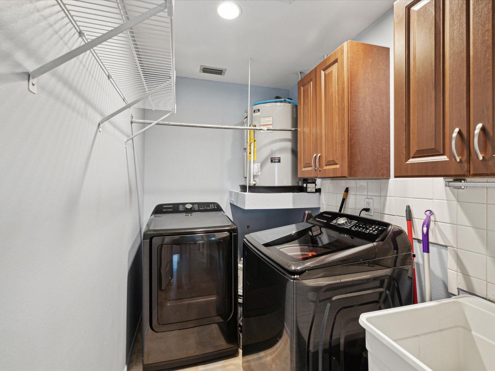 Laundry Room with tile back wall, hard wood cabinets and utility sink.