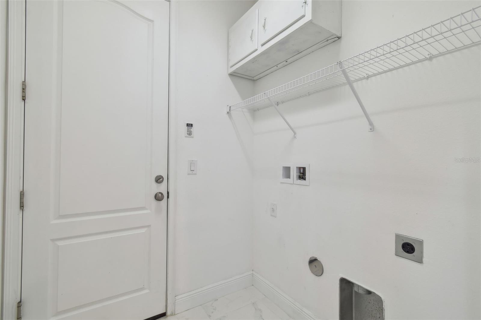 Inside laundry room with convenient shelving and cabinetry.