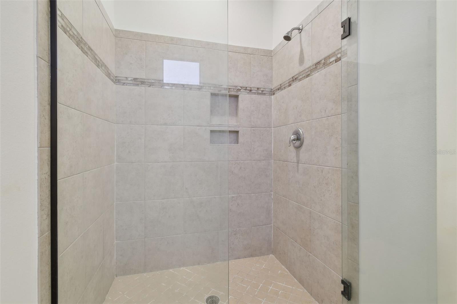 Master ensuite walk-in shower with built in tile shelves.