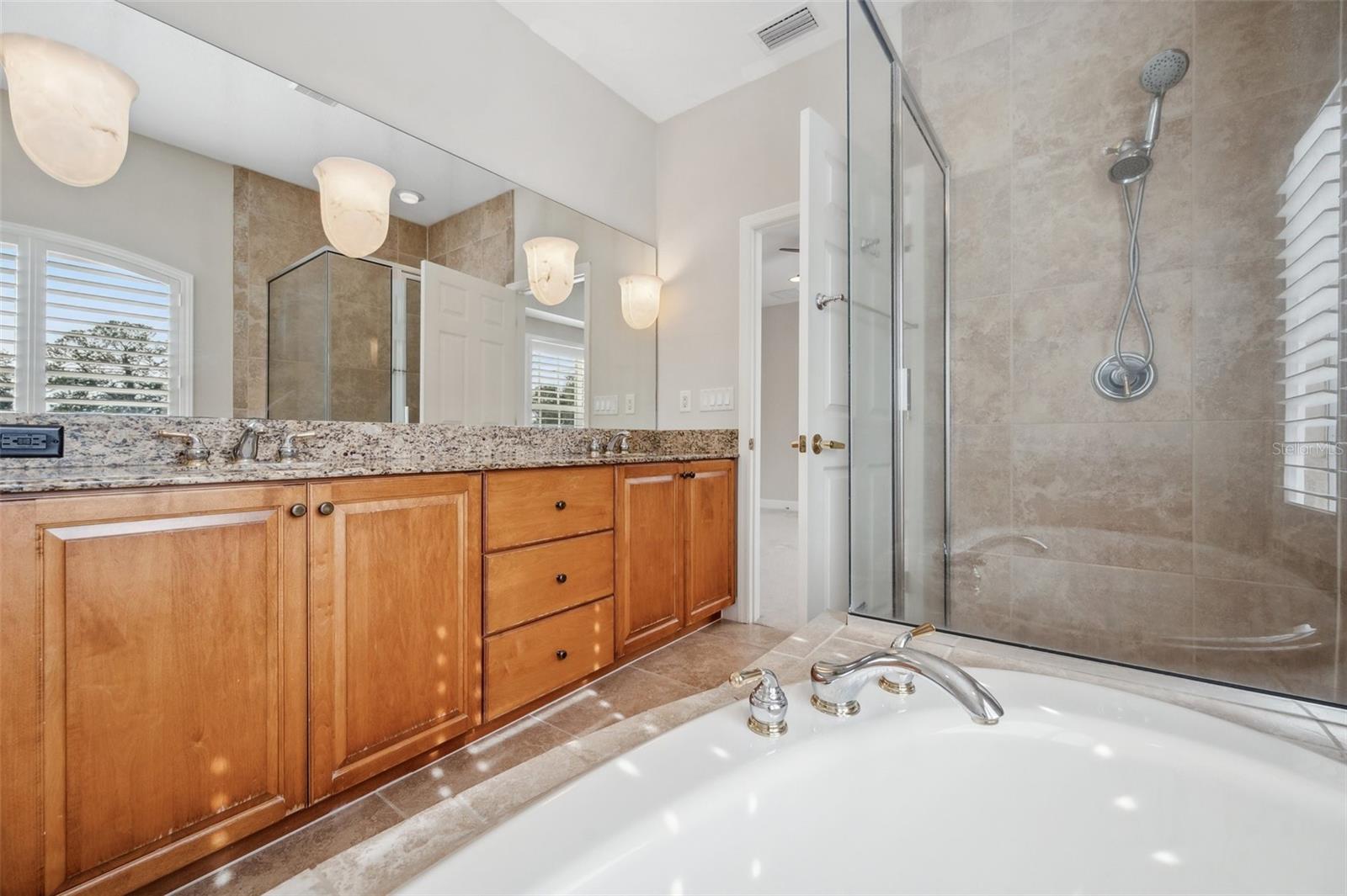 Maple cabinetry, dual-vanities, and custom lighting in Primary Bathroom