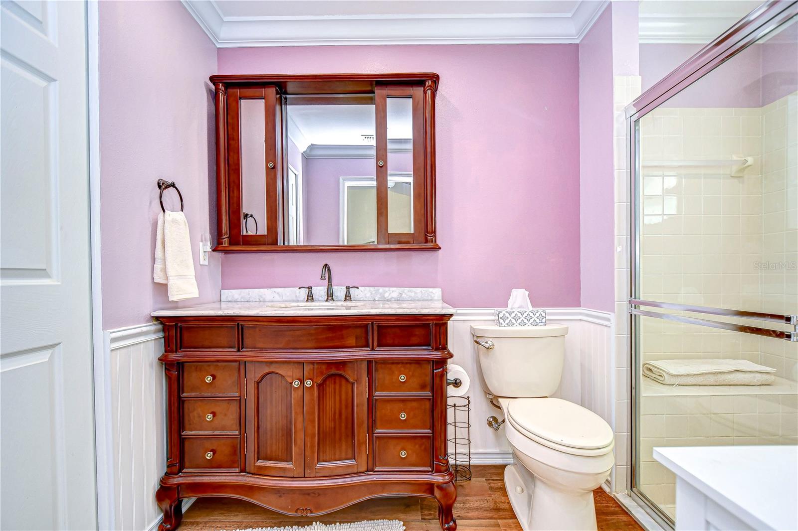 Primary bath features walk in shower, accented by wainscoting and crown molding!