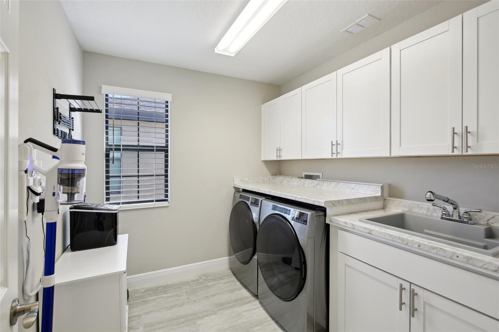 Laundry room equipped with cabinets, countertop, and sink.