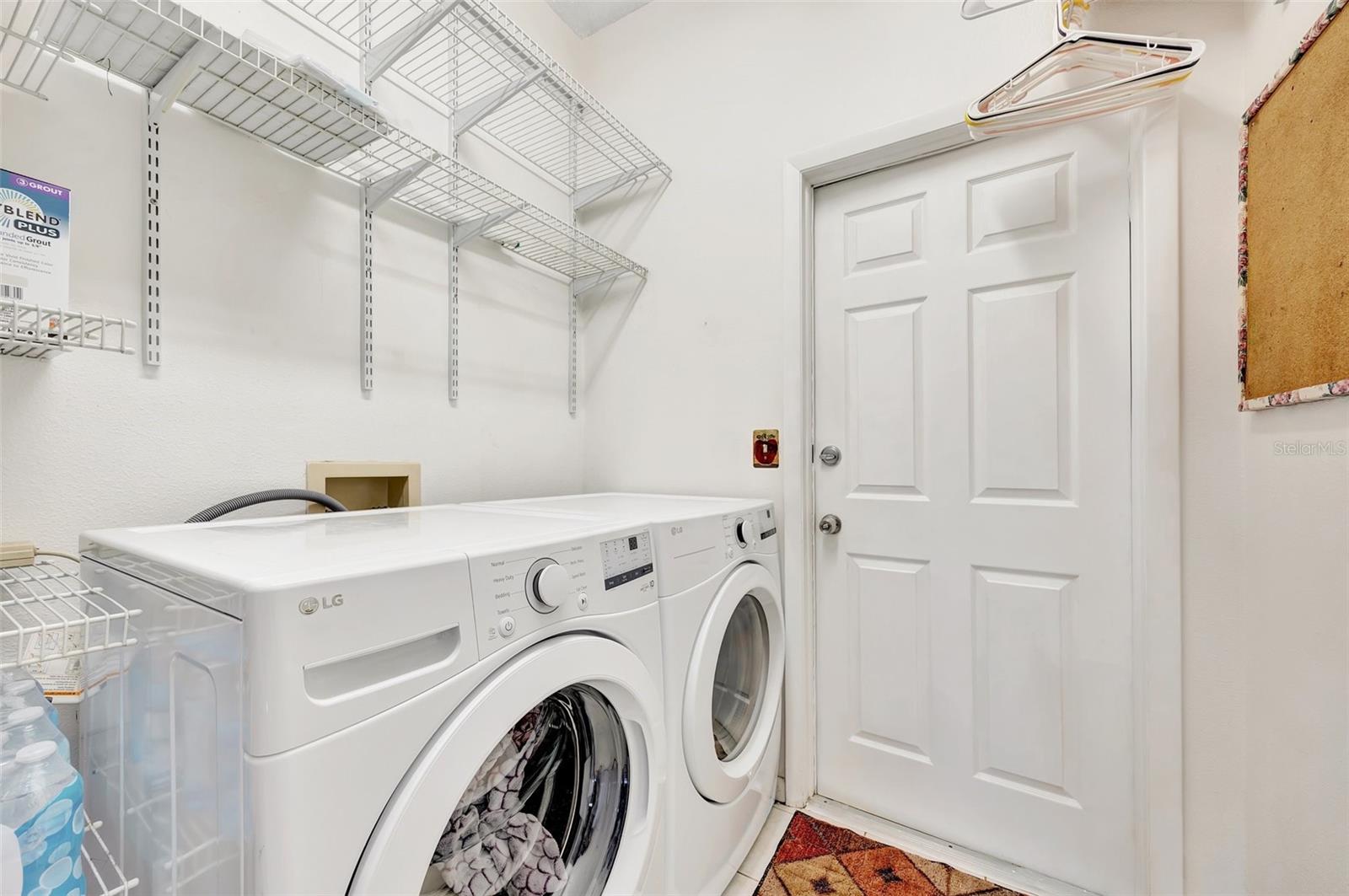 The laundry room, has shelving and an entrance from Garage into home.