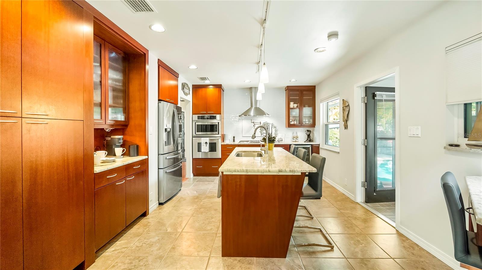 Bright and inviting kitchen showcasing sleek granite countertops, warm wood cabinetry, modern stainless steel appliances, and a central island with ample seating, perfectly designed for both functionality and style