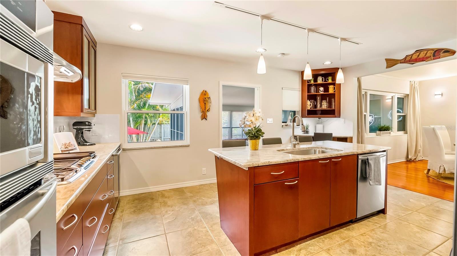 Charming kitchen with expansive granite countertops, custom wood cabinetry, a farmhouse-style sink, and large windows offering natural light and views of the lush outdoor space.