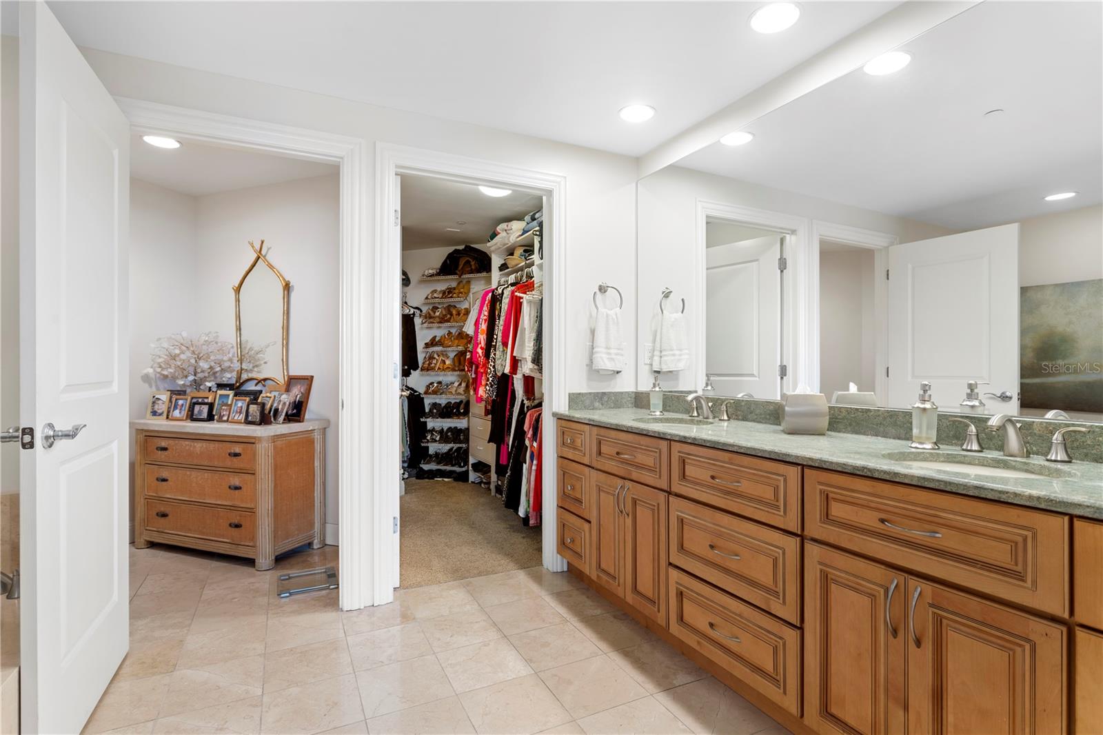 The primary bath has gorgeous cabinetry with a beautiful hand selected stone countertop and an oversized custom organized closet.