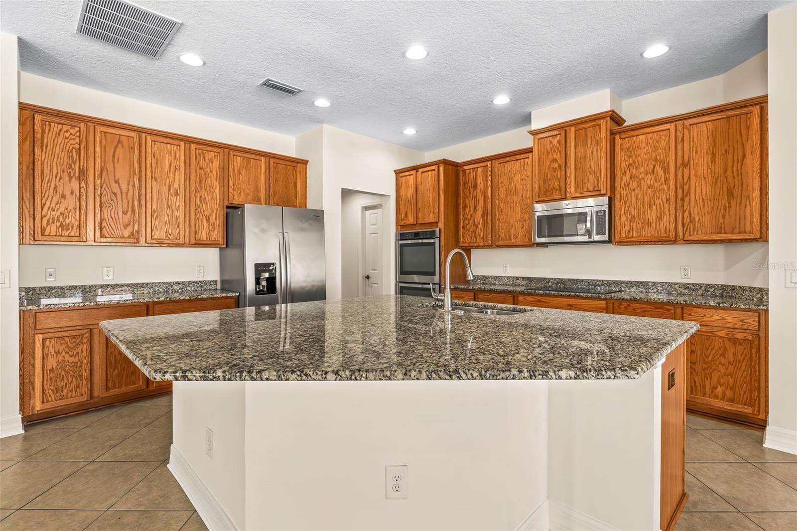 The island seats 4 against the granite countertops, 42" crowned wood cabinetry, stainless steel appliances.