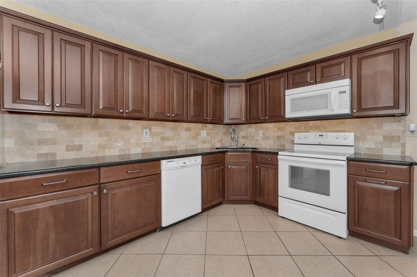 Kitchen with Cherry wood cabinets and Travertine backspash