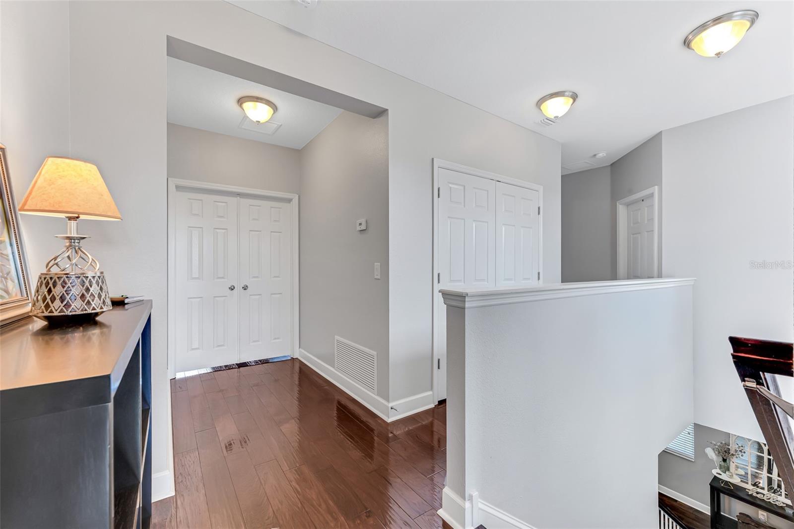 At the top of the stairs, the landing offers a private entryway into the grand primary suite, accessed through elegant double doors.