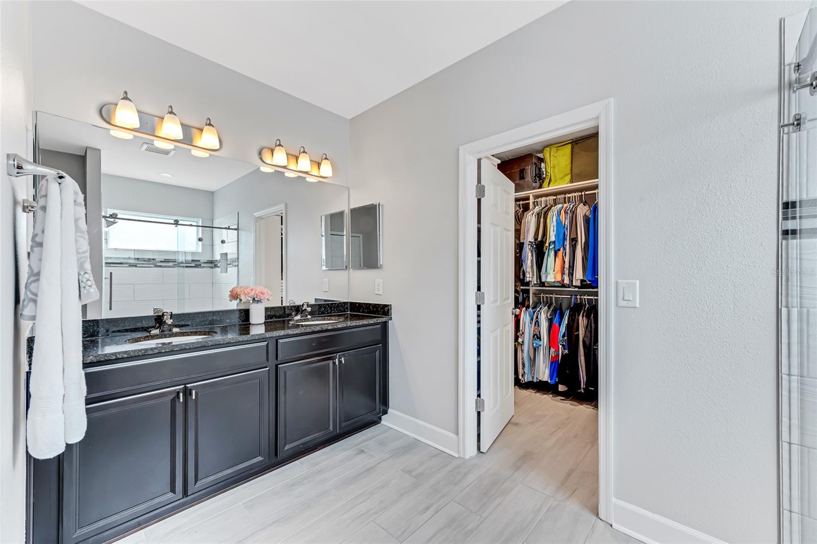 This ensuite is truly enviable, featuring dual sinks on a granite vanity and a spacious 7' x 11' walk-in closet with custom shelving installed.