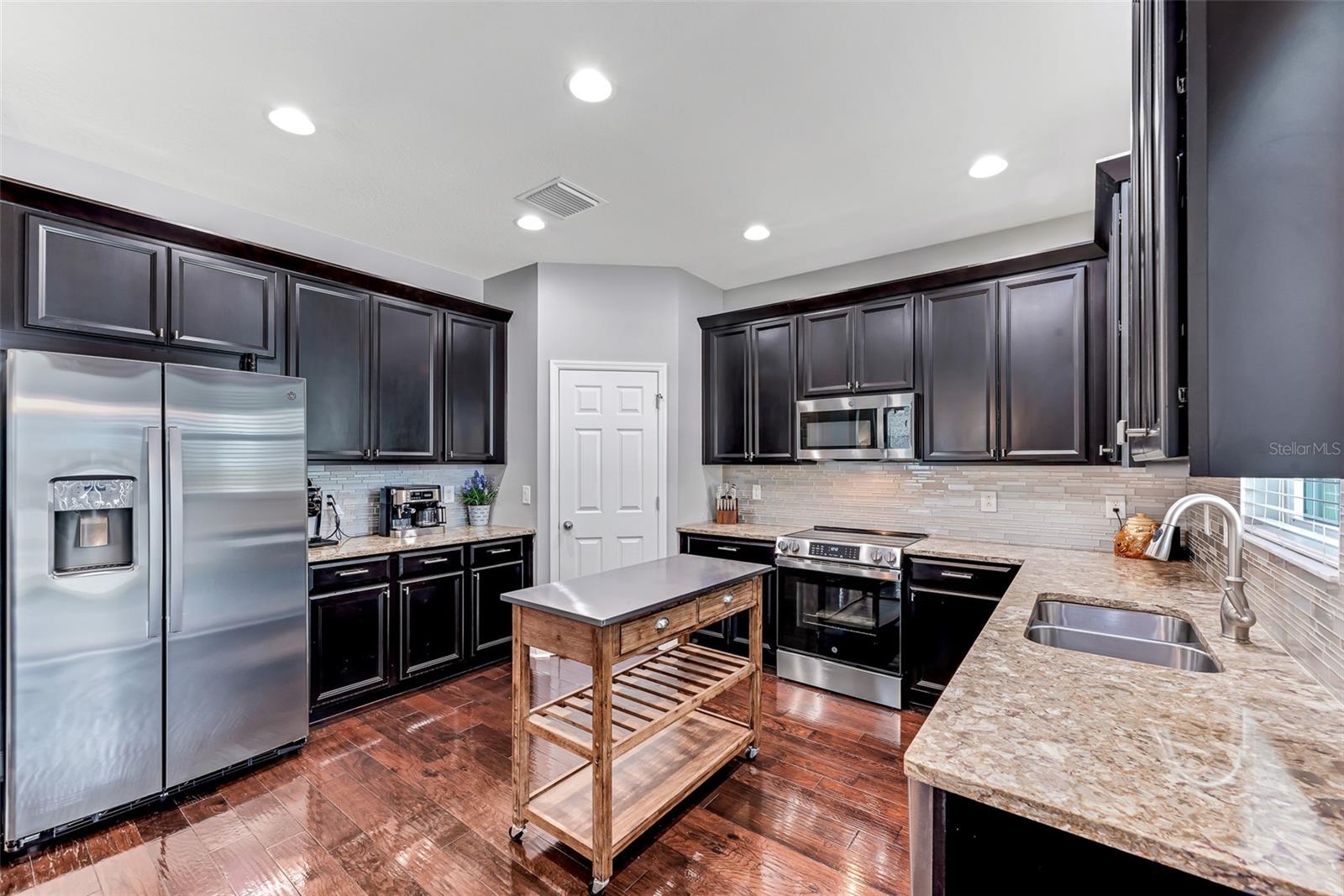 The gourmet kitchen features 42" Espresso cabinetry with crown molding, top-of-the-line stainless steel appliances—including a convection oven—and stunning granite countertops complemented by a stylish sea glass tile backsplash.