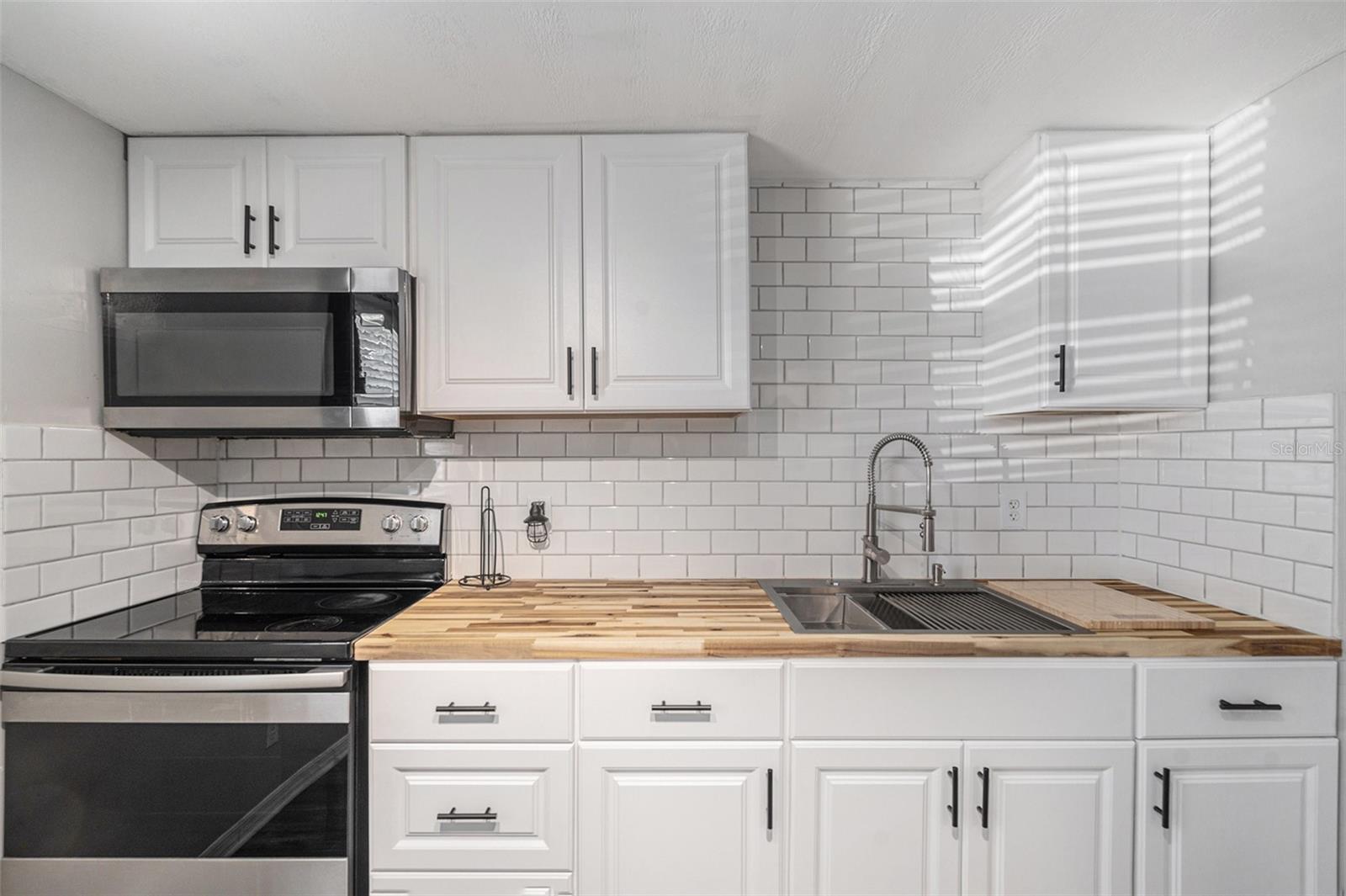 Stunning butcher block countertops and a stainless steel workstation sink