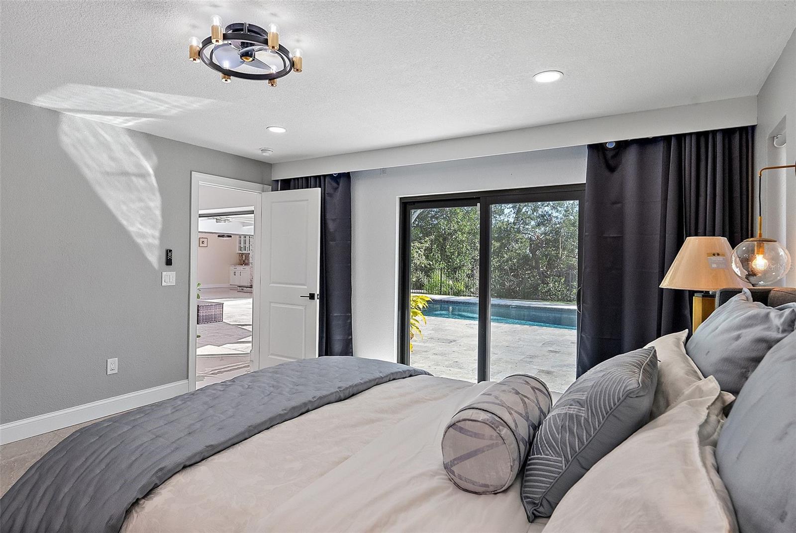 Primary bedroom overlooking pool and patio