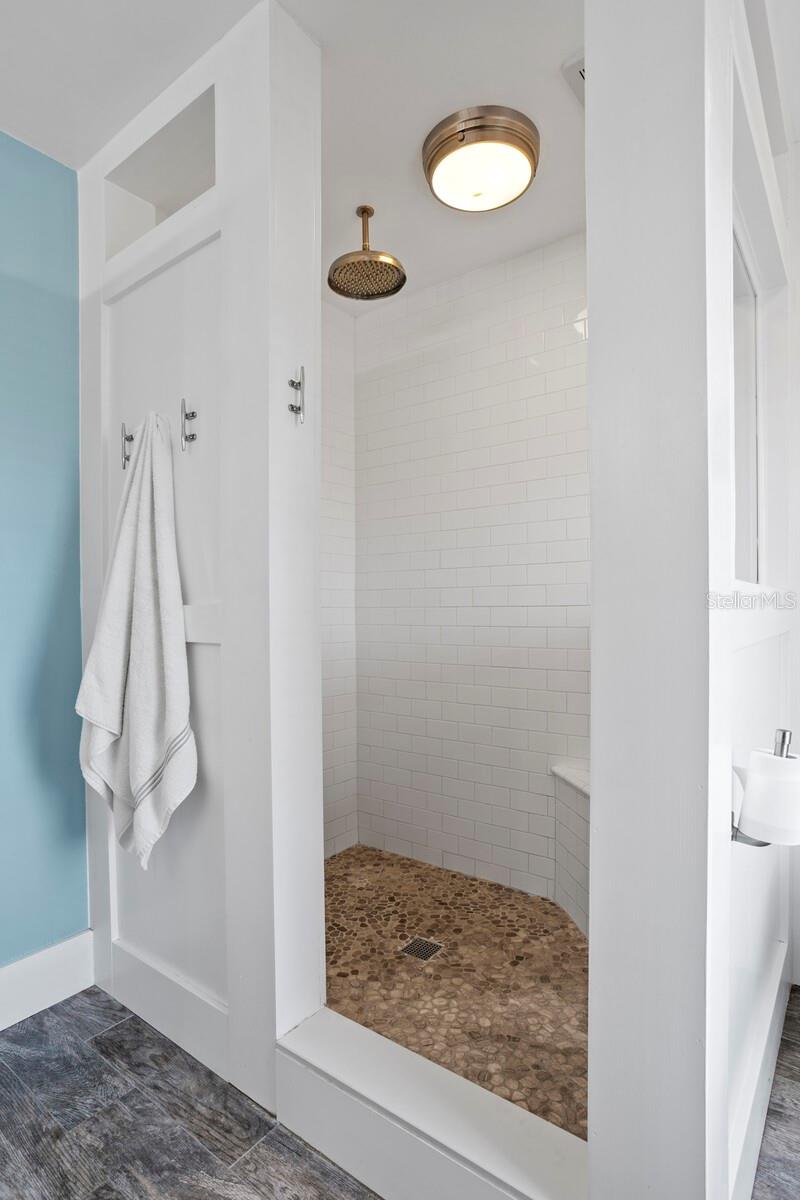 The large walk-in shower includes subway tile and a rain shower head