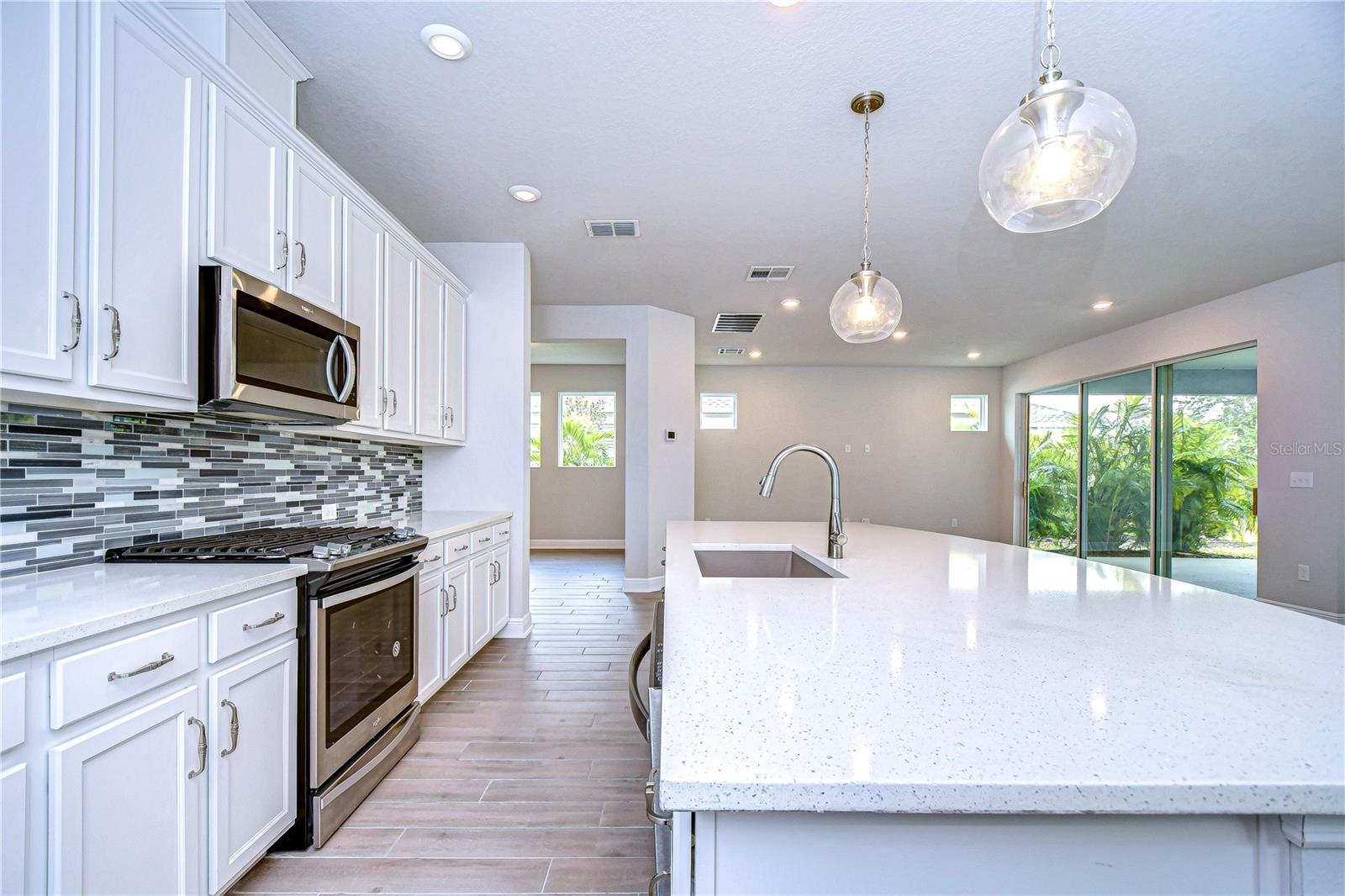 Statement lighting, gorgeous cabinets and a tiled backsplash provide a gorgeous aesthetic.