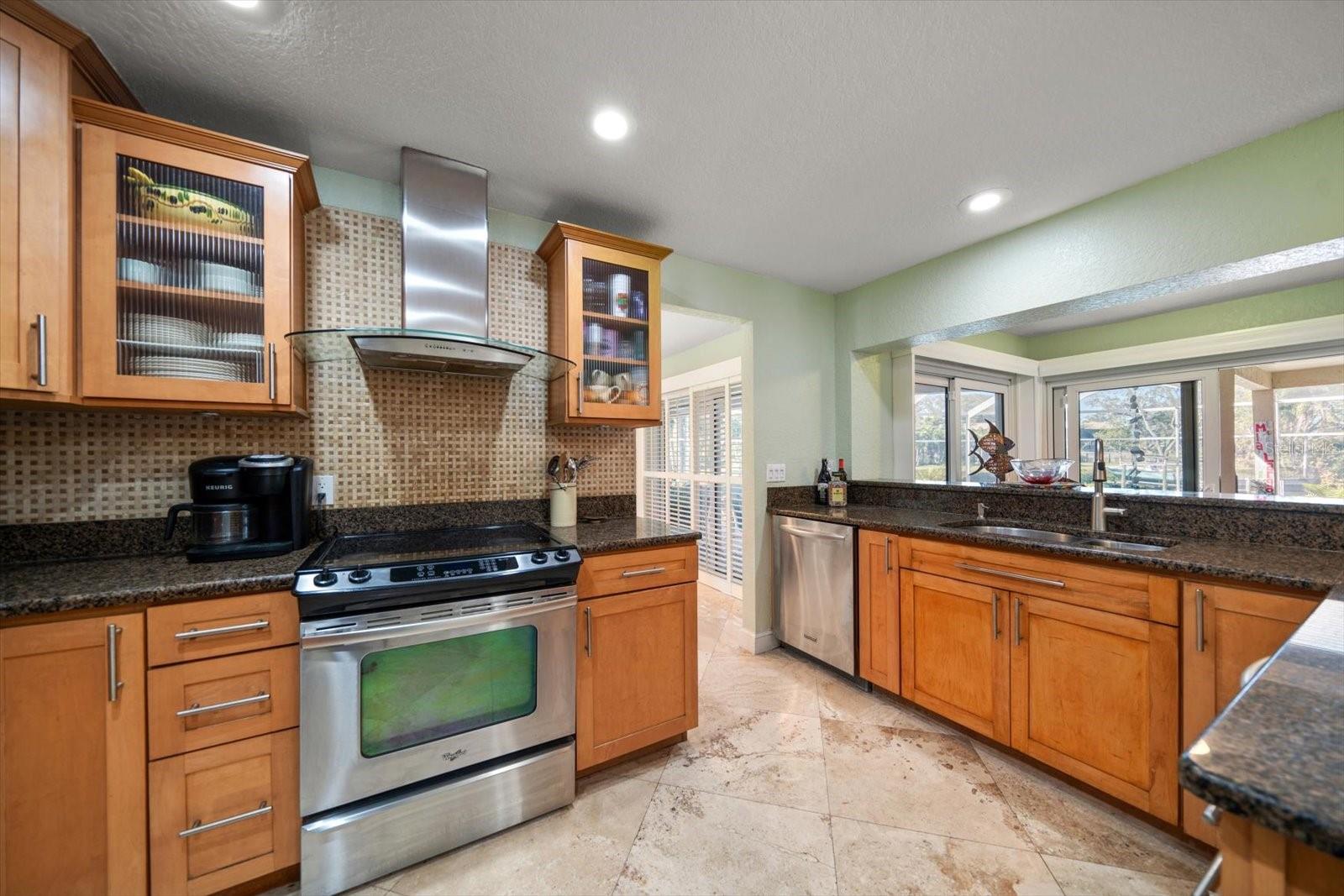 A well-thought out kitchen such as this one with high-end finishing's like the stone backsplash, etched class storage cabinets, and abundant storage and counter space is a dream for any chef!