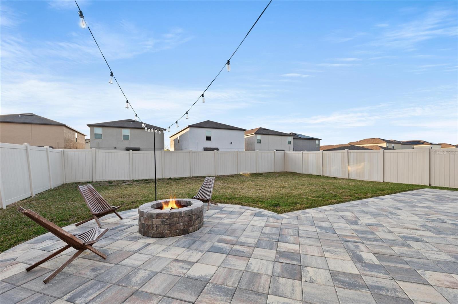 Custom built-in fire pit on paver patio and fully fenced backyard.