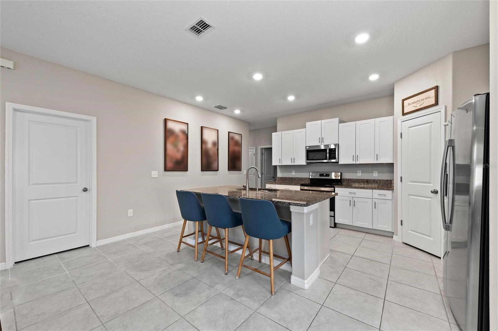 Kitchen has granite island, stainless steel appliances and a corner pantry.