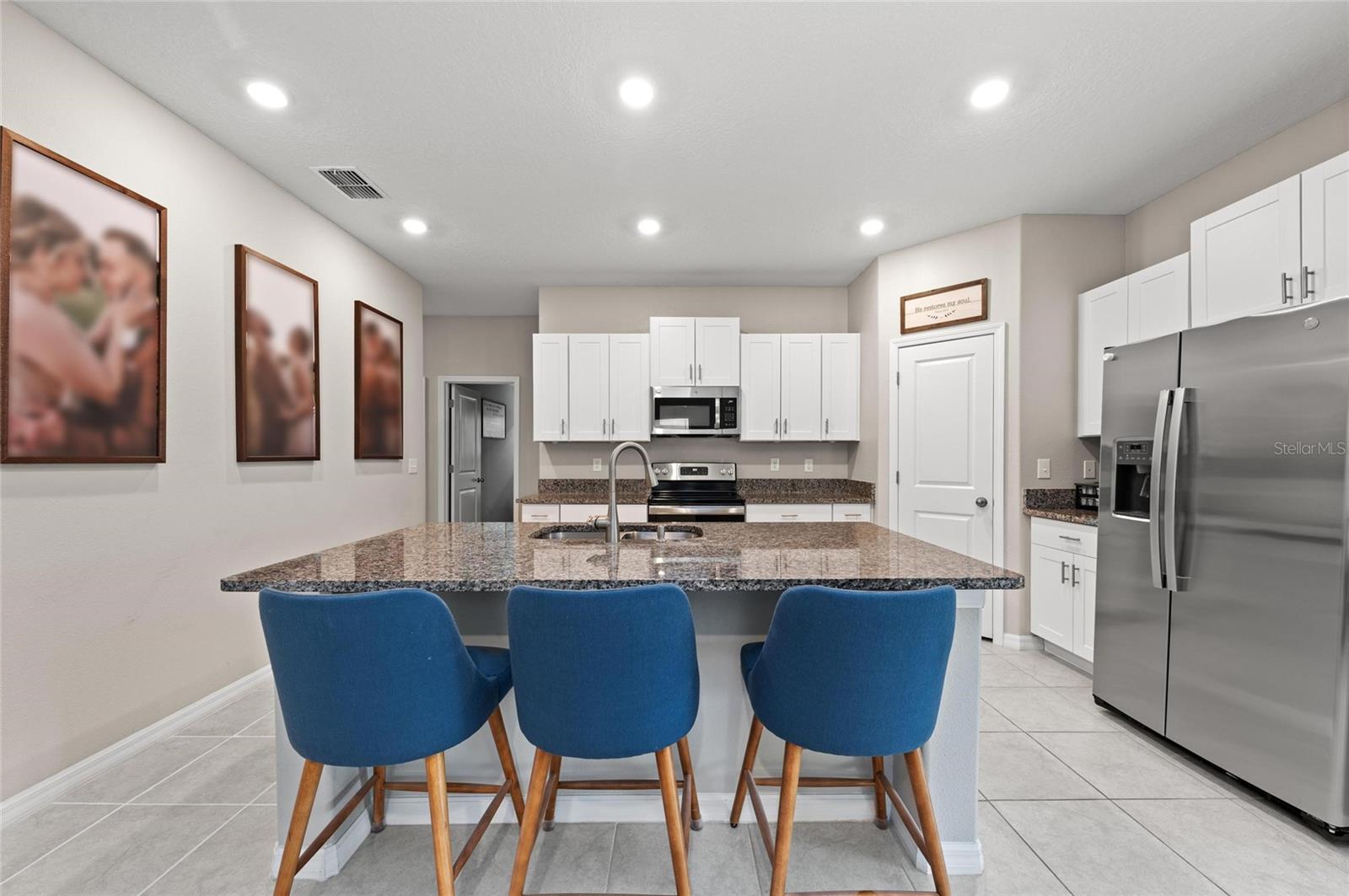 Kitchen has granite island, stainless steel appliances and a corner pantry.