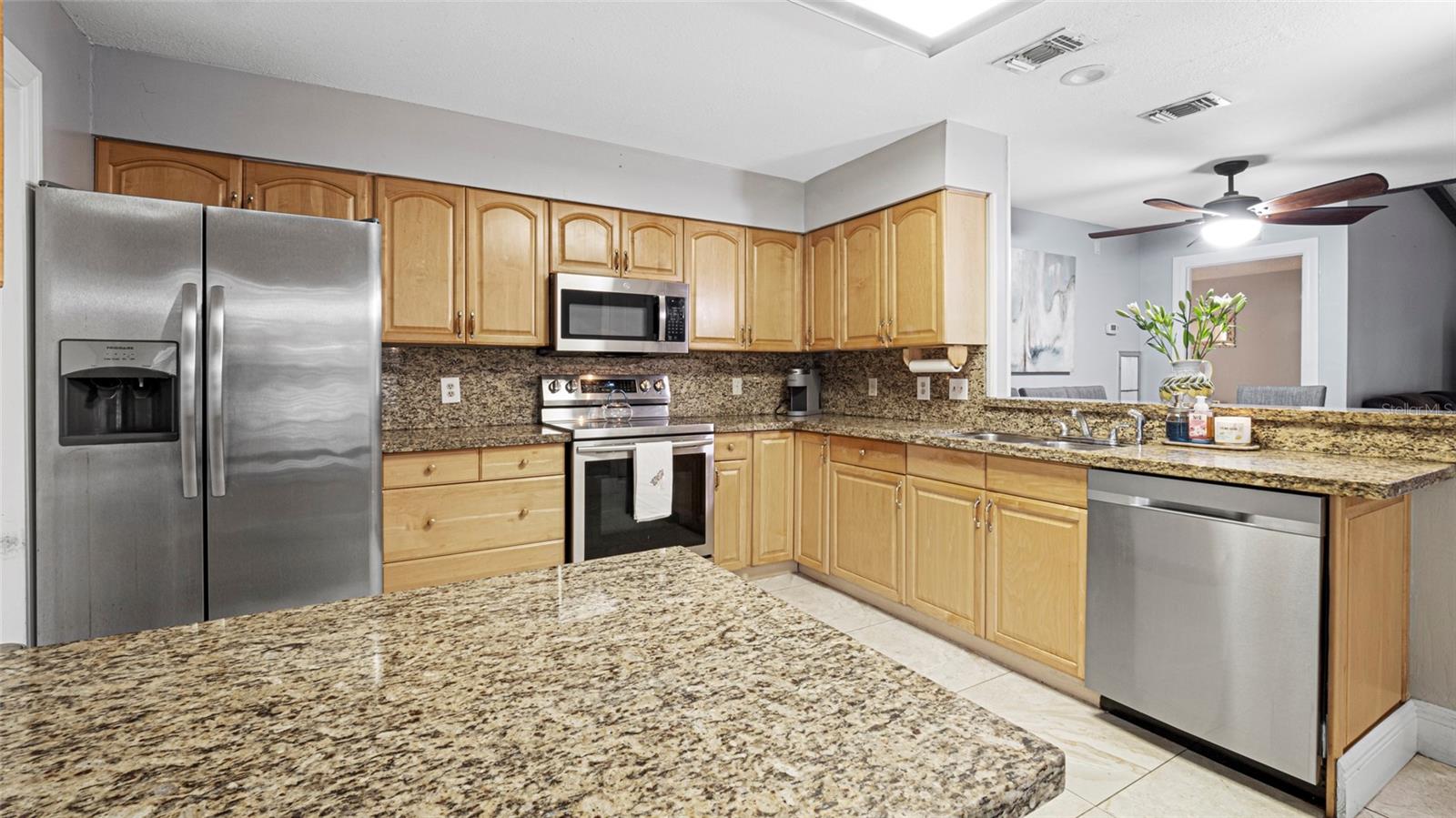 Spacious kitchen, with granite countertops, warm wood cabinetry, and stainless steel appliances.