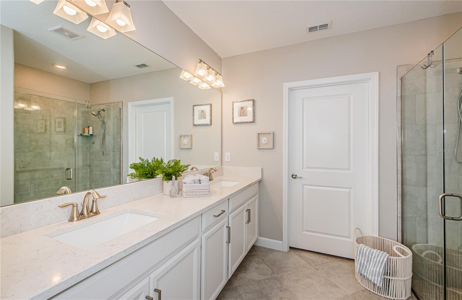 The en-suite bathroom offers a spa-like experience with an oversized walk-in shower, dual-sink quartz vanity, and elegant lighting. Just beyond, discover a large walk-in closet, providing ample space for wardrobe organization and storage. This thoughtfully designed suite ensures comfort, privacy, and everyday luxury.