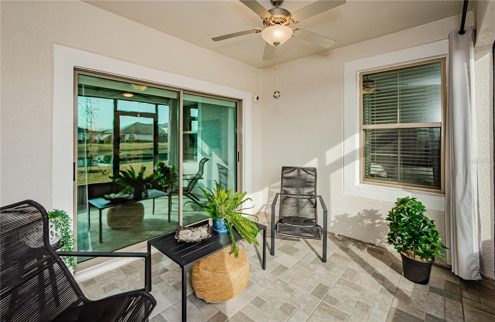 Step into your own private retreat where comfort meets tranquility. This screened-in back porch is the perfect space to sip your morning coffee while soaking in breathtaking water views. Enjoy the gentle Florida breeze under the cooling ceiling fan, while modern black seating, lush greenery, and an elegant curtain add a touch of sophistication. Whether entertaining guests or unwinding with a book, this seamless indoor-outdoor living space is the perfect complement to Mirada’s 55+ lifestyle.