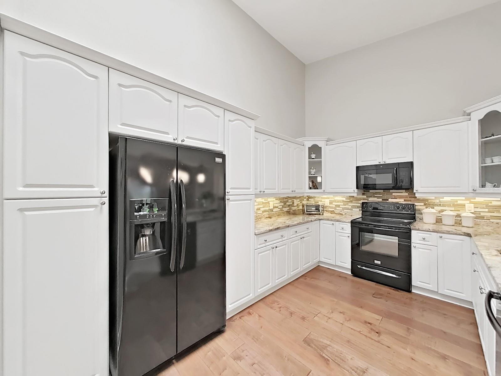 Tastefully updated Kitchen with raised panel cabinetry, modern backsplash, and granite counters.