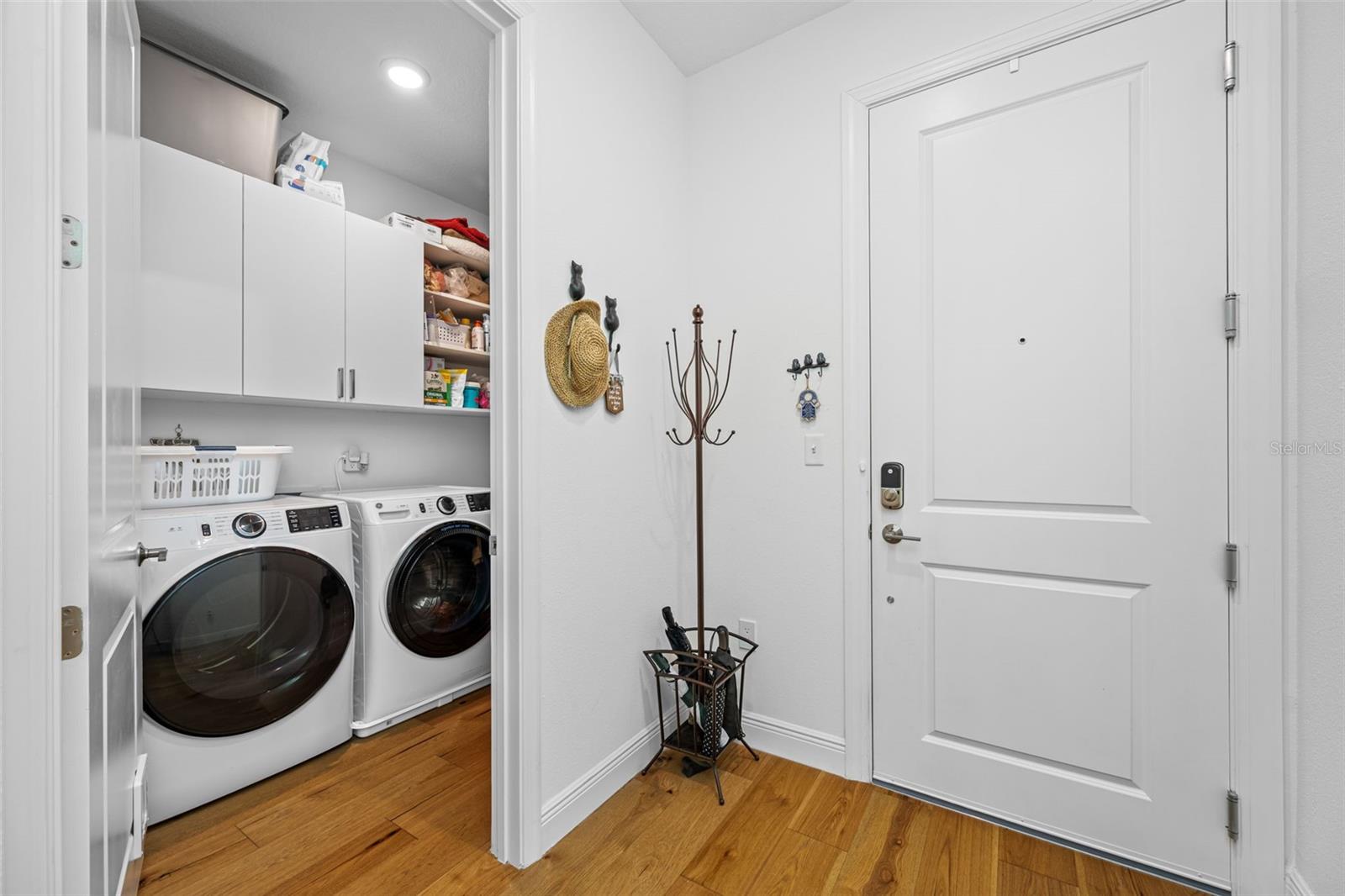 Full-size Laundry room with custom cabinetry is tucked away discreetly near front entry