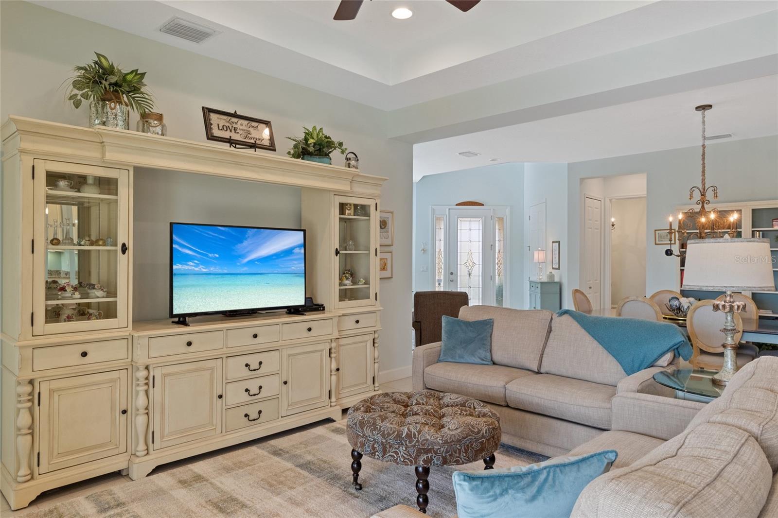 Tiled living area with tray ceilings, recessed lighting & ceiling fan