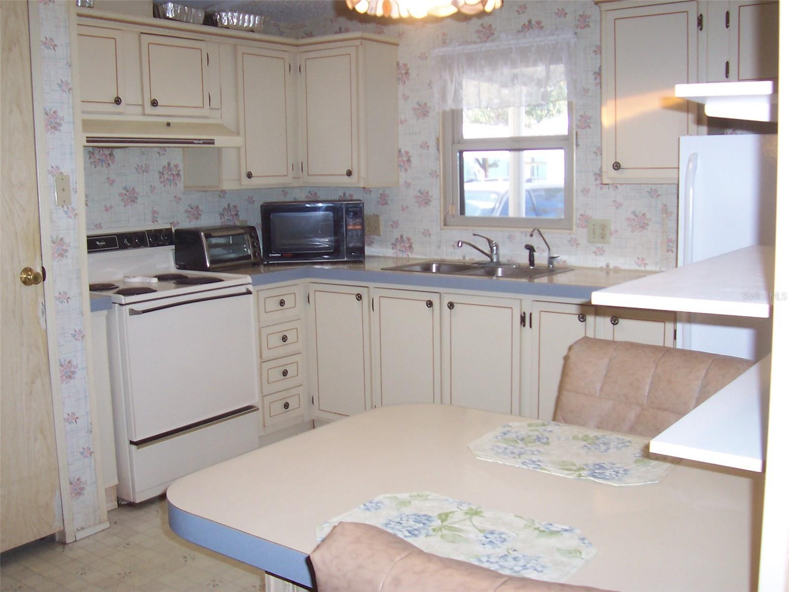 Step saver kitchen featuring eat in breakfast bar for quick meals on the go.   Nice window lets in natural light over the kitchen sink.