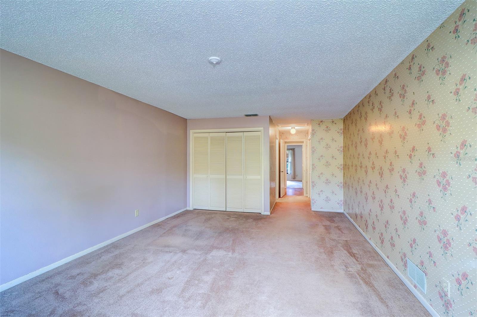 View from the outside wall of the primary bedroom looking at one of the double door closets into the hallway