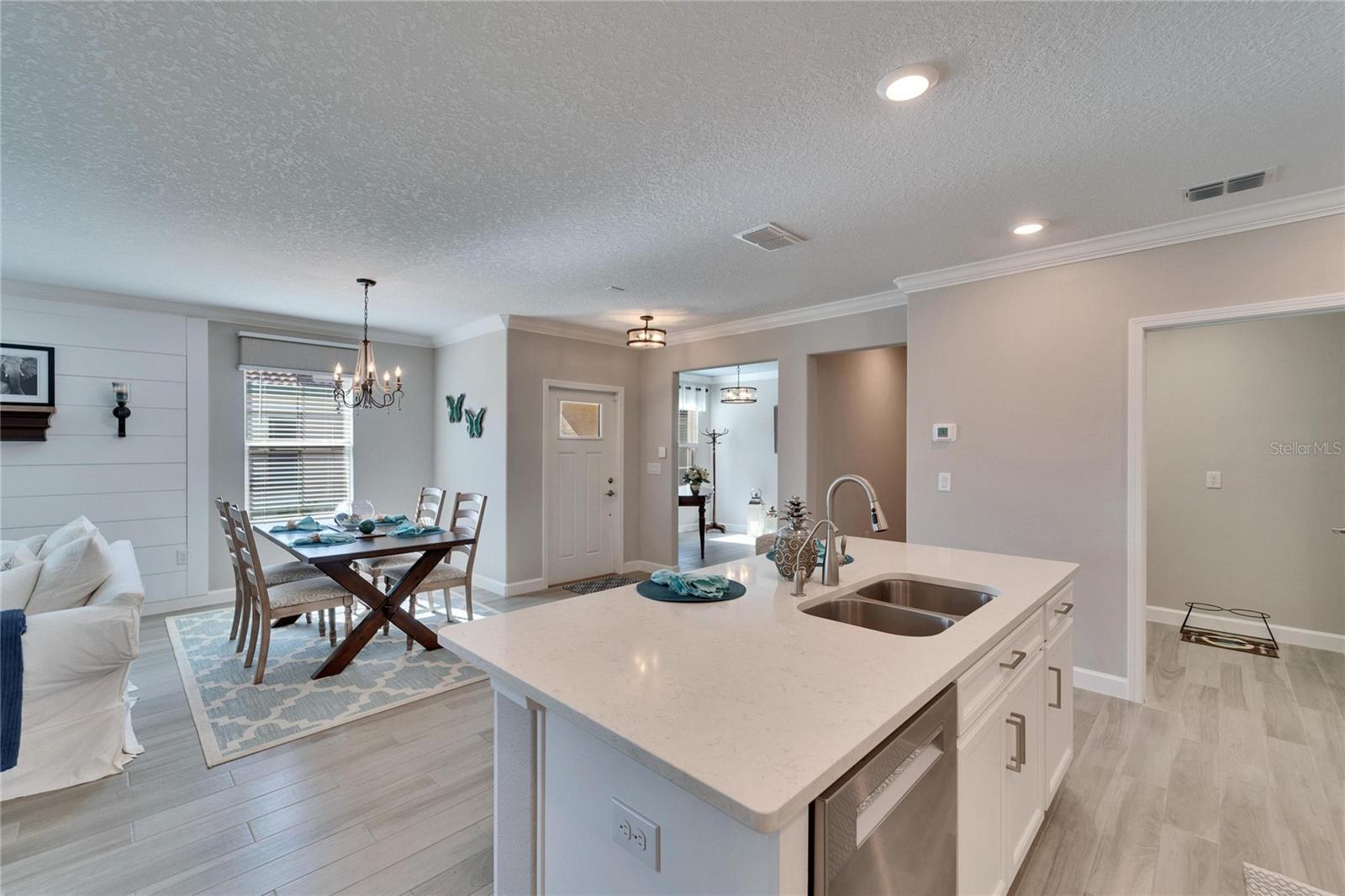 The white door to center right is the front door. Doorway behind the kitchen island is the home office/ den.  Door to the far right is the laundry room.