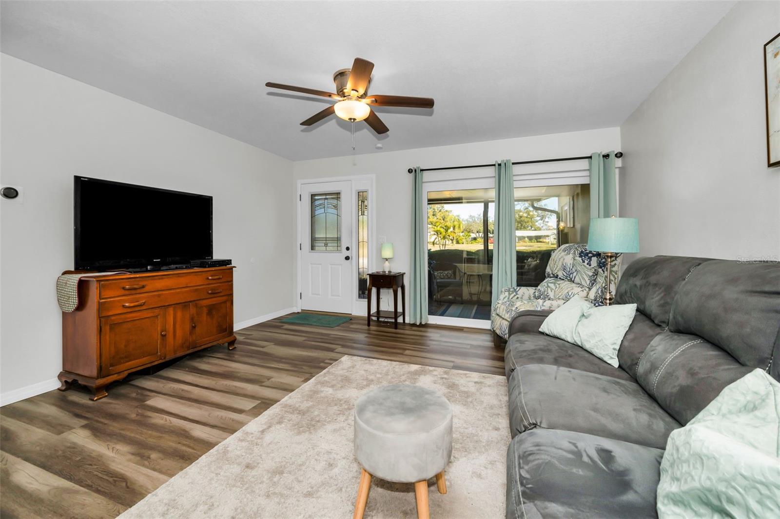 Comfortable Living Room with ceiling fan and slider access to the front Screened Lanai.