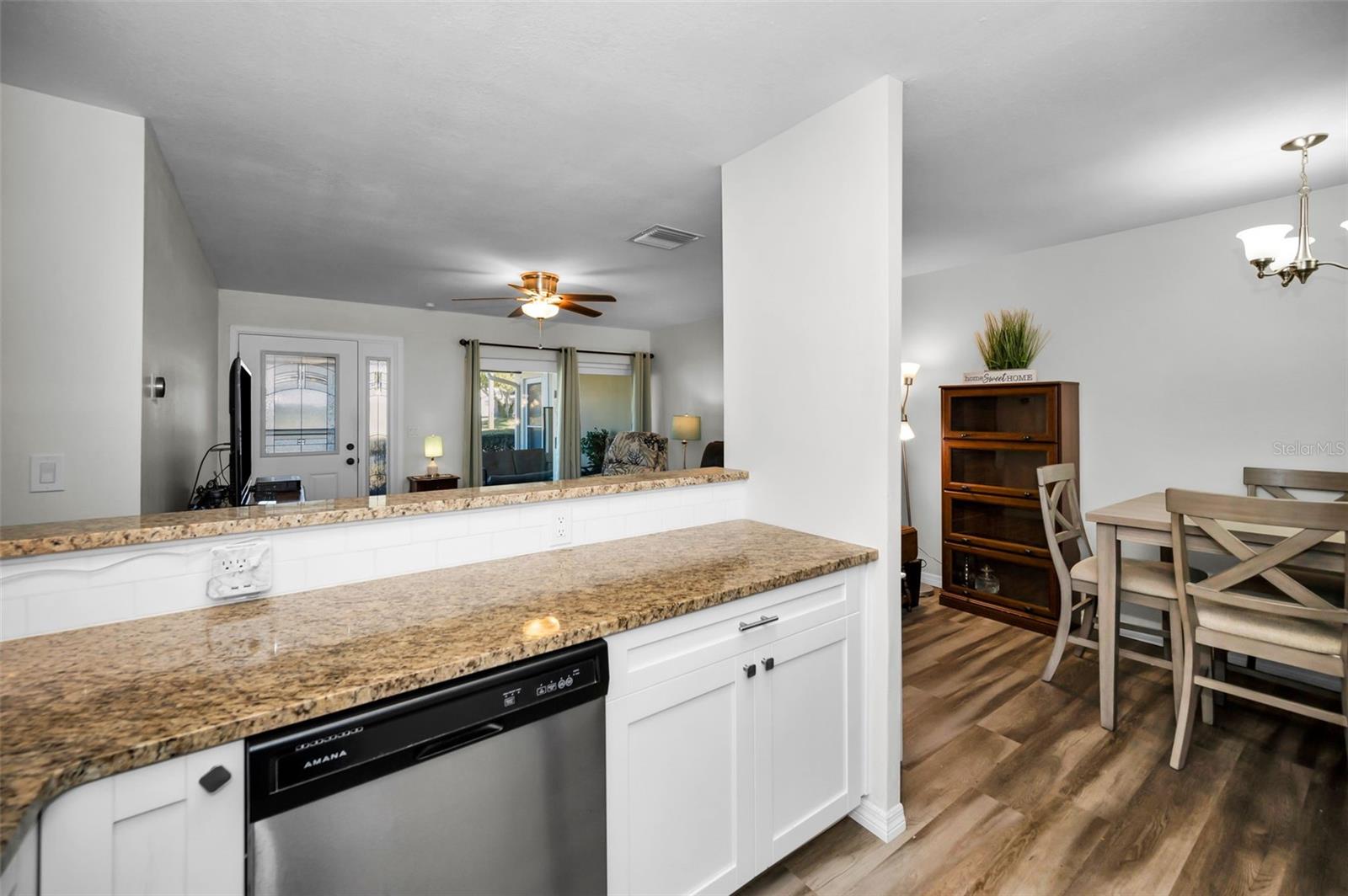 Expansive granite countertop that stretches seamlessly, offering both ample workspace and a clear line of sight into the spacious living room.