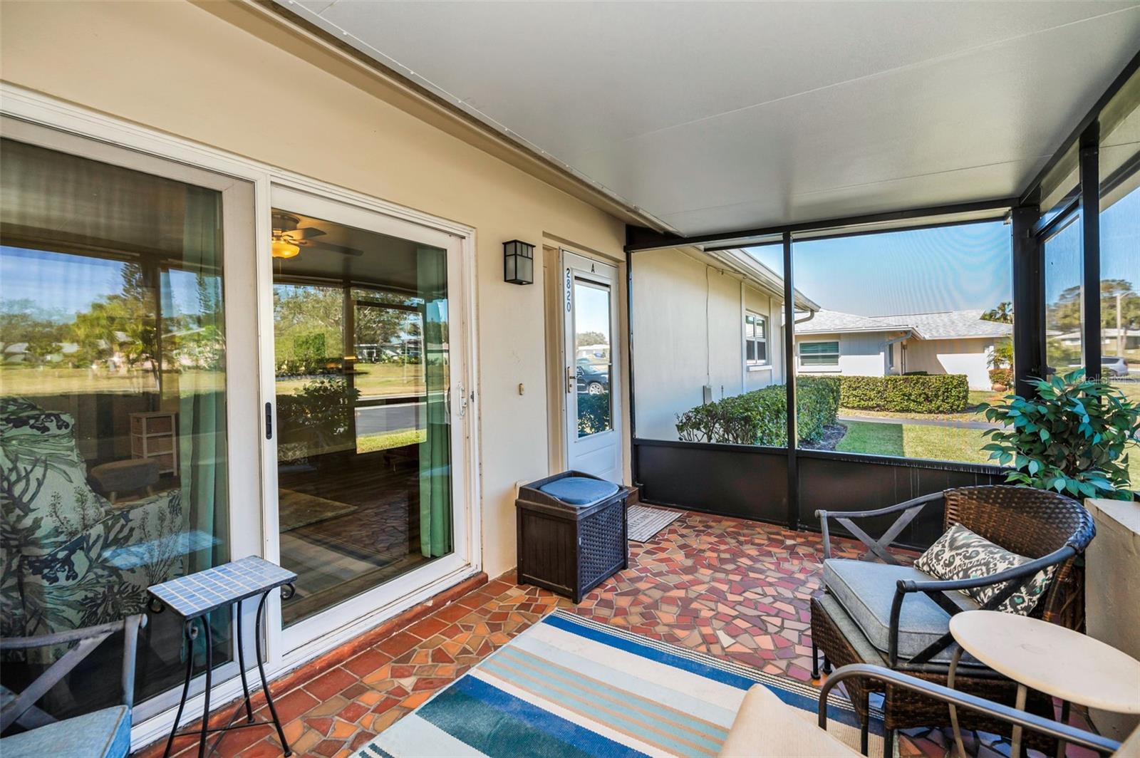 Screened Lanai with classic tile mosaic flooring. Front door is on the far side.