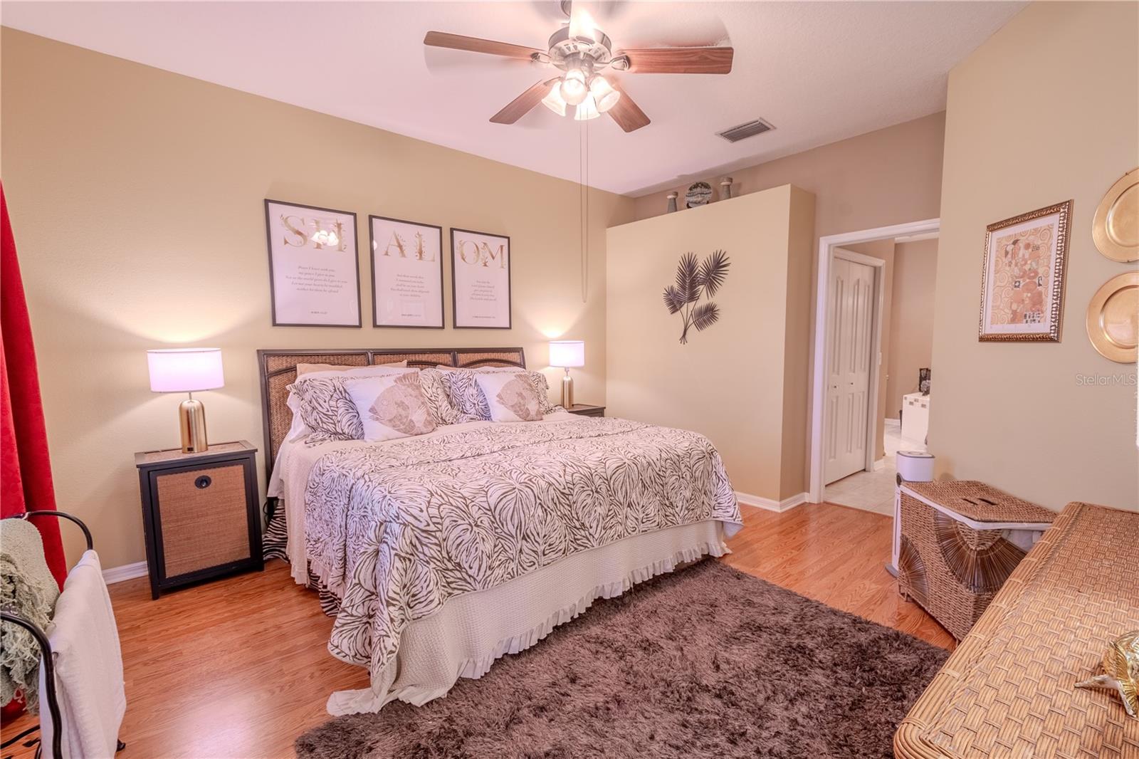 The primary bedroom features wood laminate flooring, a ceiling fan with light kit, a walk-in closet and an ensuite bathroom.