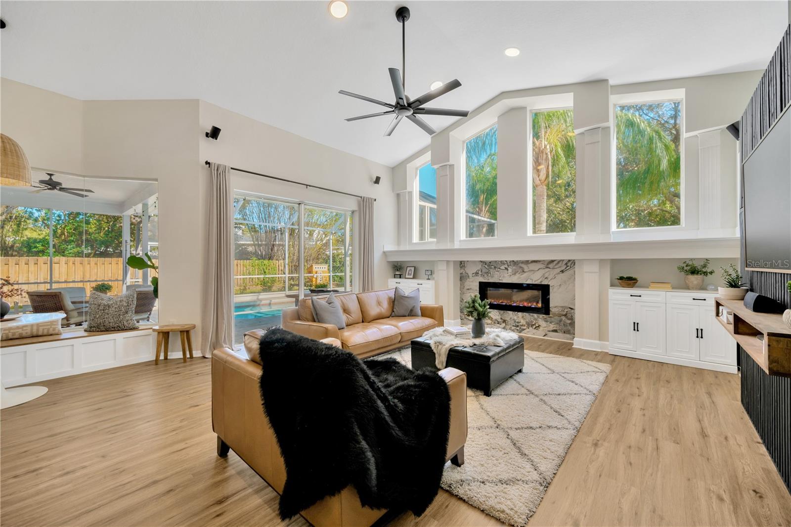 The family room is designed for both style and comfort, with custom cabinetry framing a stunning and practical built-in decorative fireplace under a wall of transom windows flooding the home with natural light.