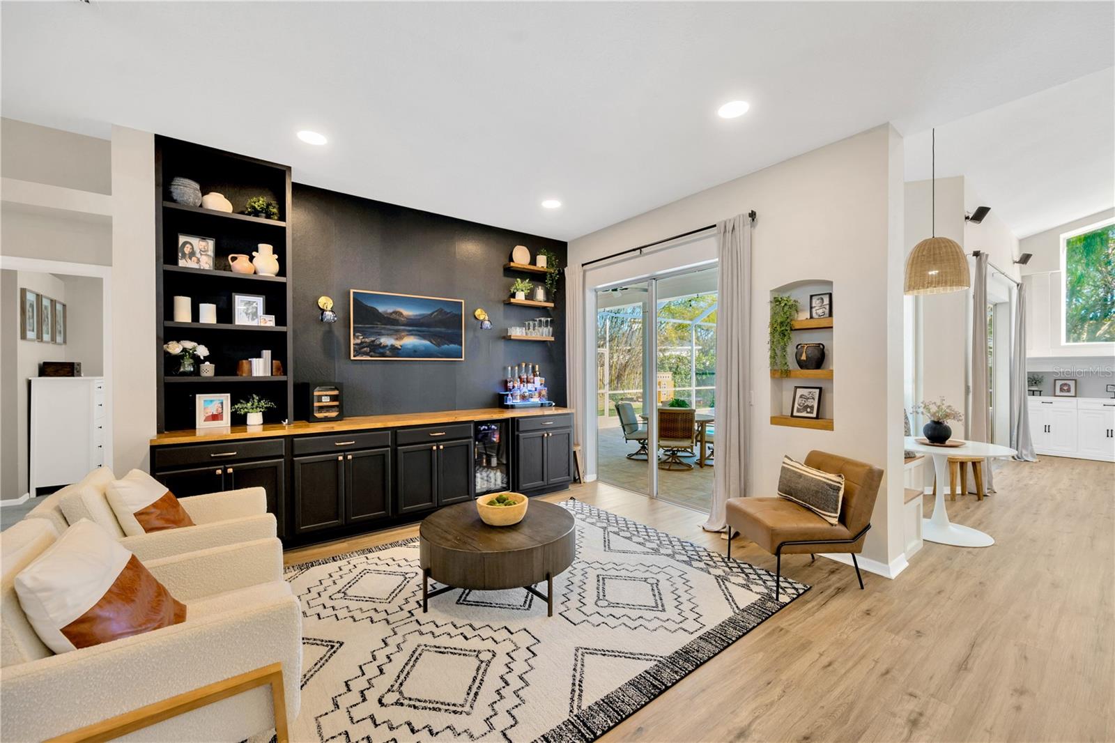 In the living room overlooking the patio & pool, you'll find extra storage in a wall of custom shelving & cabinetry with a wood-stained topper and floating wood shelves, plus a dedicated spot for a wine refrigerator making entertaining inside & outside, a breeze