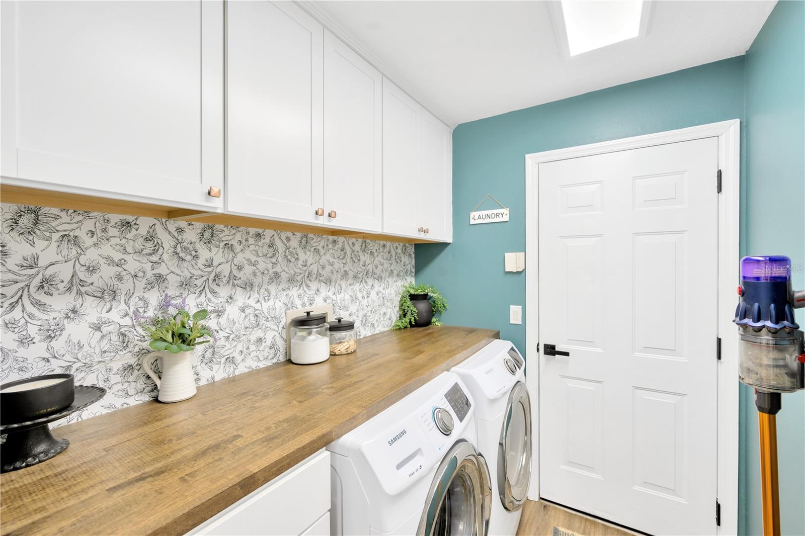 This fashionable laundry room with additional built-in storage and custom countertop leads conveniently from the kitchen to the garage.