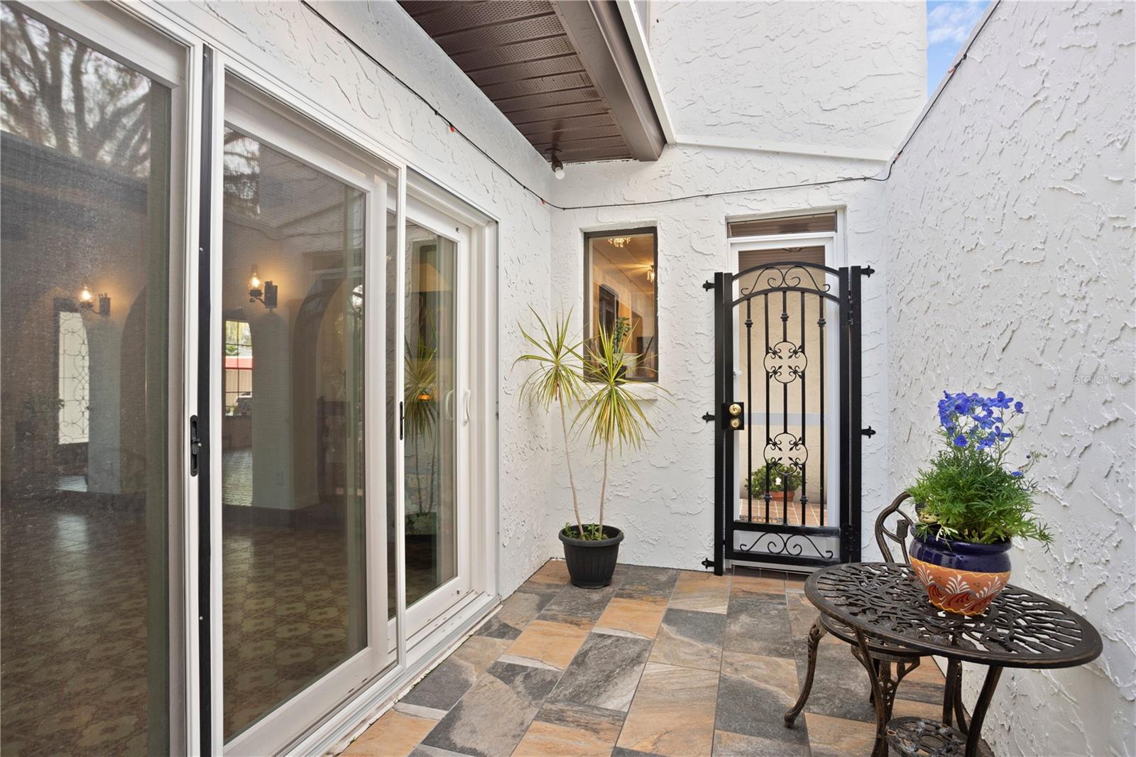 Front courtyard entry lounge with new triple sliding doors ti bonus living room entertaining space .