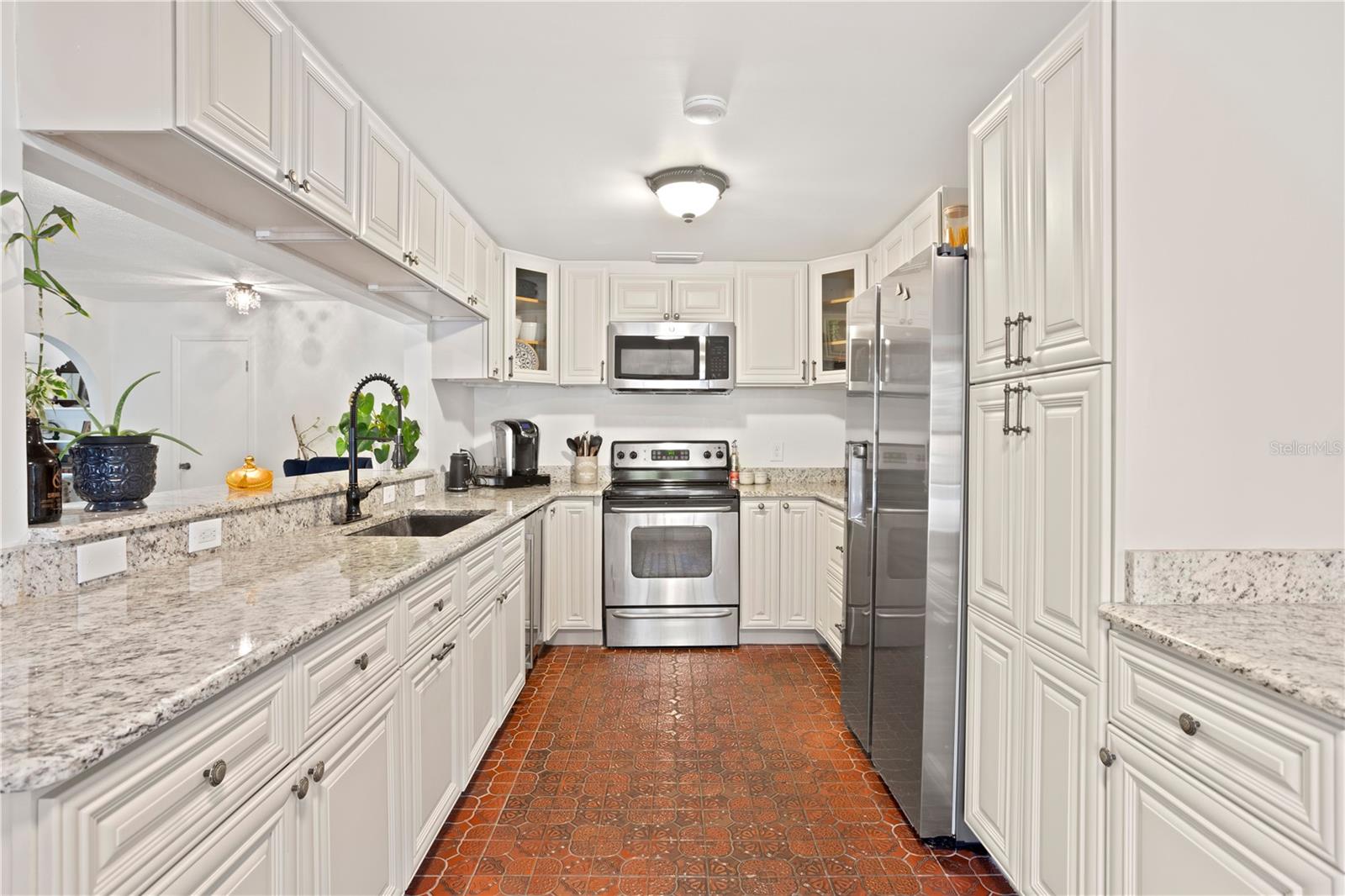 Kitchen with stone counters, wood cabinetry , wine refrigerator and breakfast bar seating to dining room