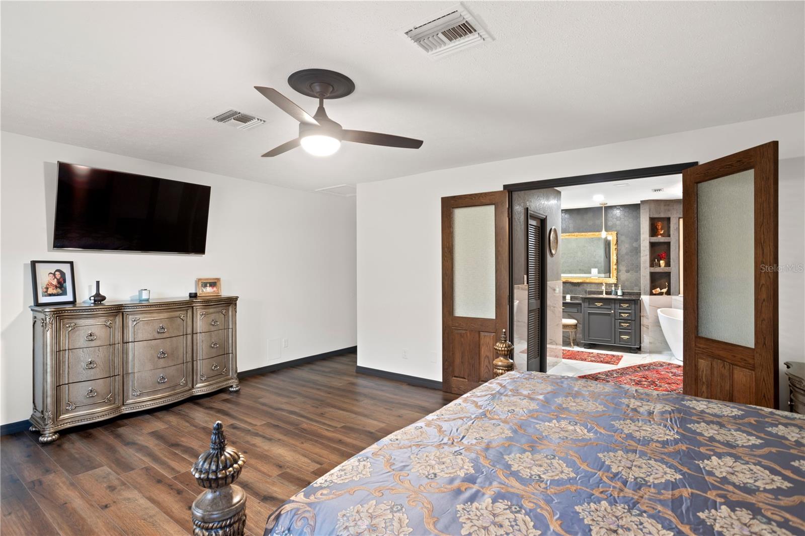 Master bedroom with bamboo flooring blackout custom remote shades and en suite bathroom