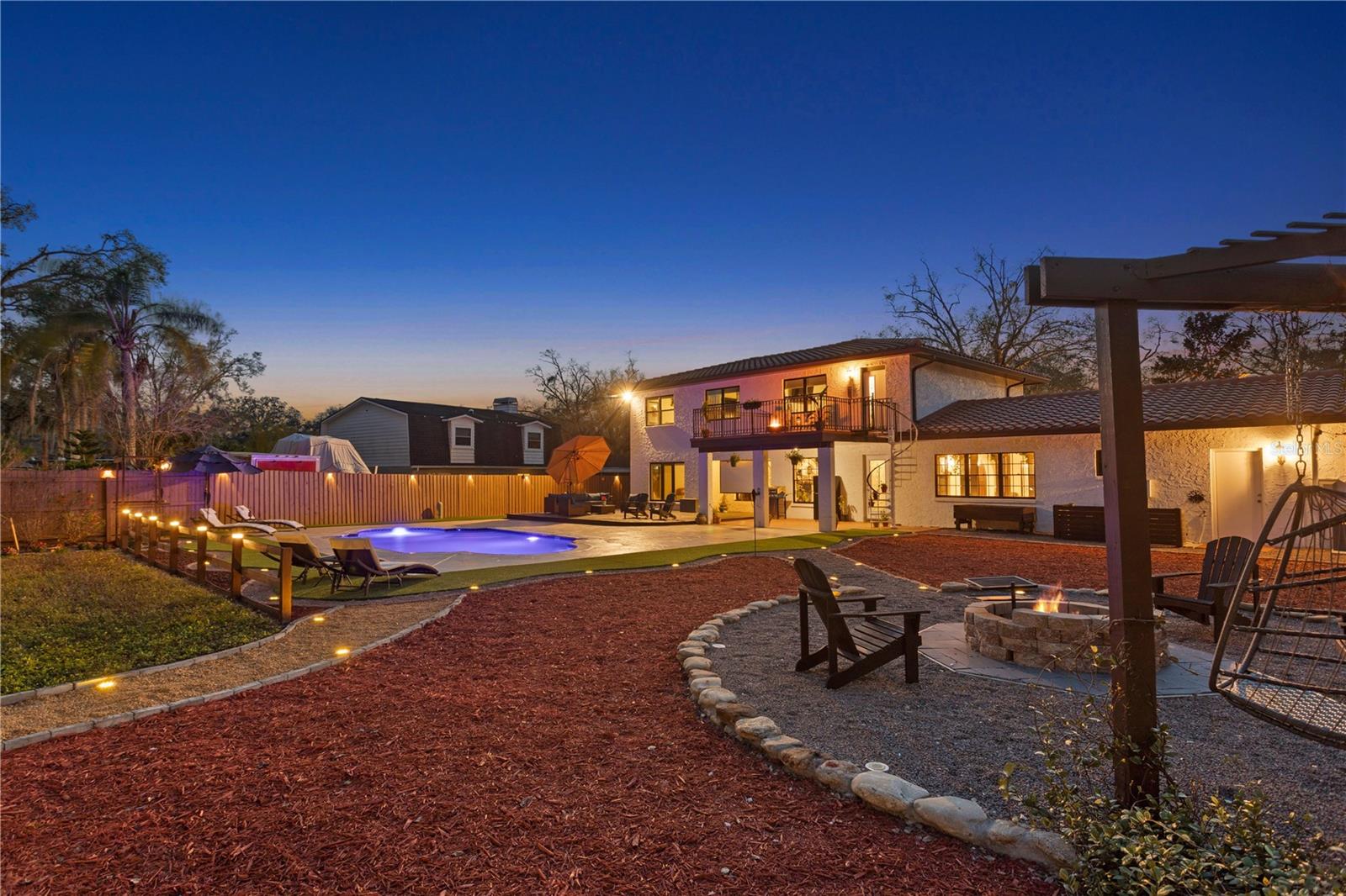 Exterior backyard trail to fire pit lounge area over looking pool , butterfly garden and exterior deck .