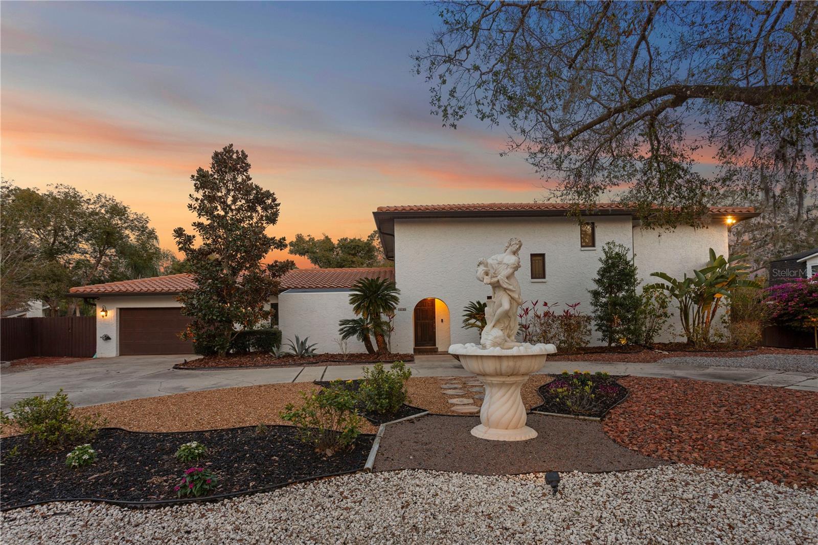 Front twilight sunset exterior . Features tile roof , from screened patio and 2 car garage with convenient circular driveway .